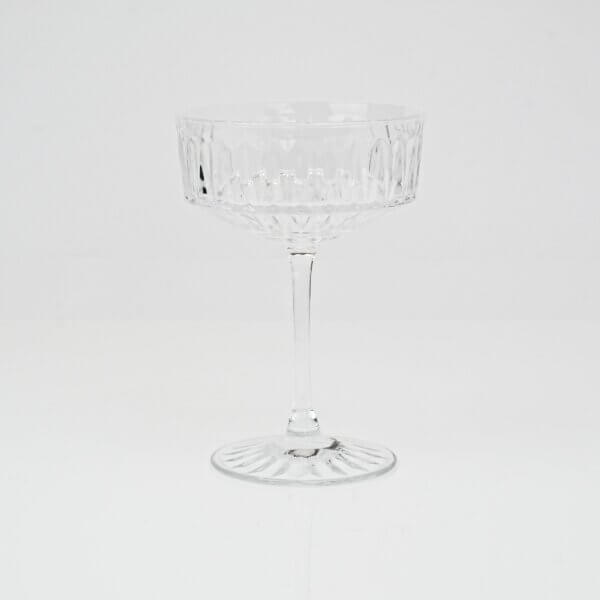 Clear glass champagne coupe glass sitting on white background