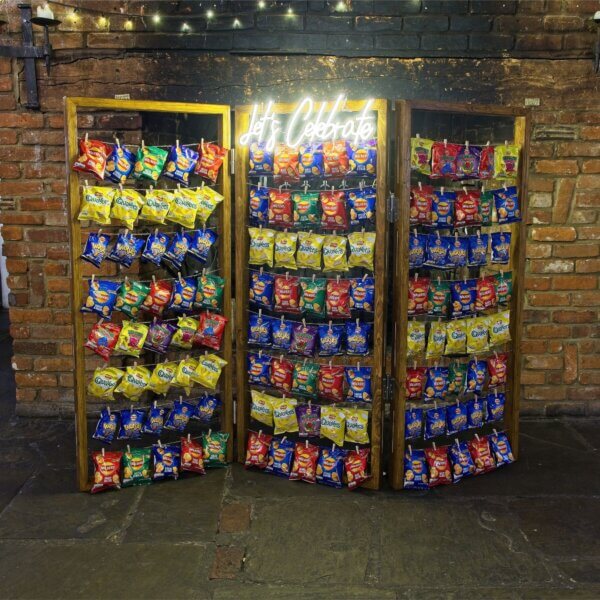 Crisp wall, full of various packets of crisps, with a lit LED sign stating; "Let's Celebrate"