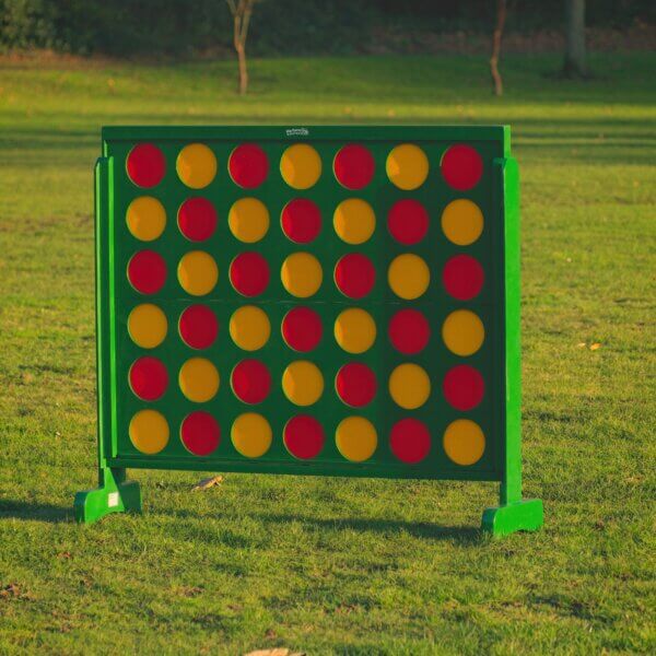 Giant connect 4 seen standing outside. The frame of the connect 4 is green and filled with red and yellow counters. The counters are arranged in a red then yellow pattern.