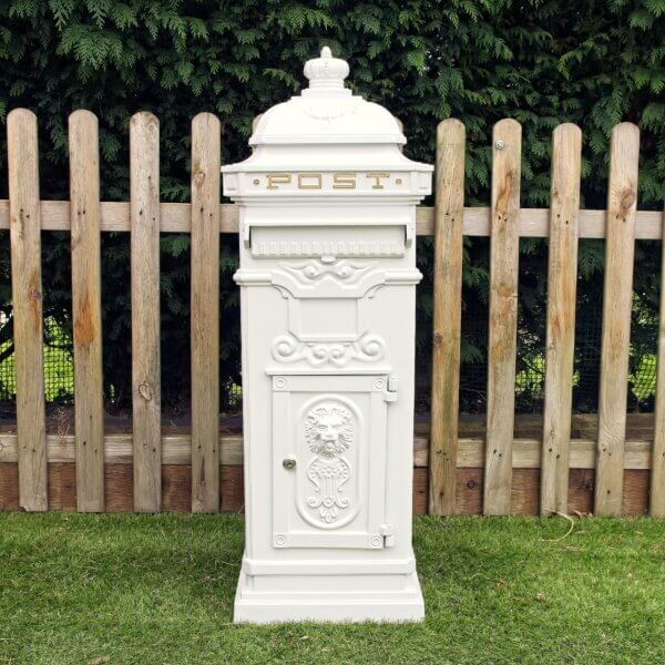 White ornate metal post box pictured outside. Lock shown of a front door of the post box with a embossed lions head visible, a flap for post and gold written "Post" at the top