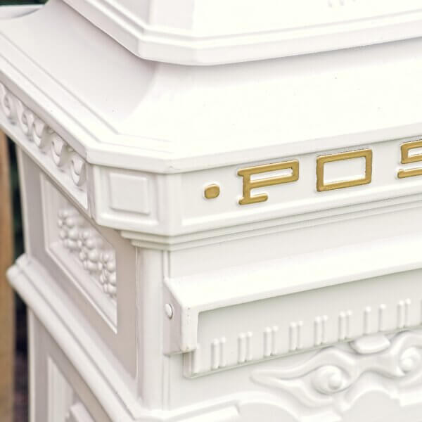 Close up of white metal post box with only "Pos" visible of the top writing and the side of the flap showing.