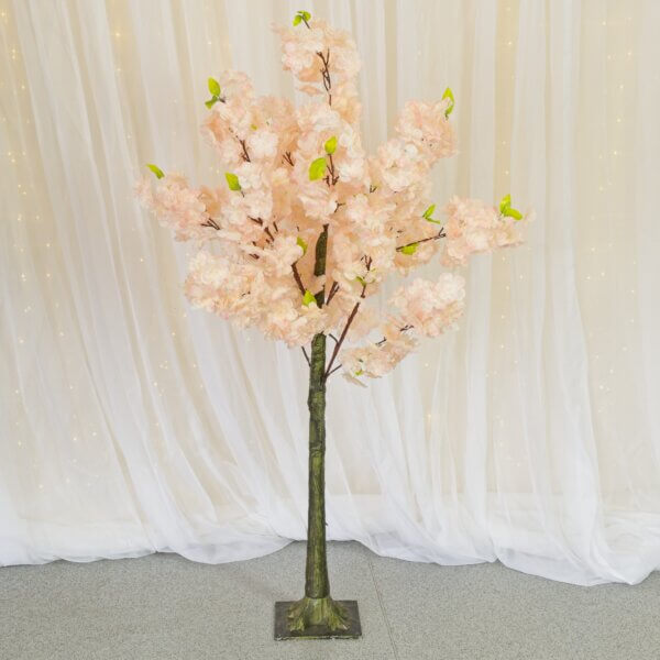 Faux pink blossom tree and in front of a white drape backdrop with curtain lights behind