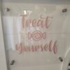Clear acrylic sign with pink vinyl lettering saying "Treat Yourself", mounted to the front of the sweet cart