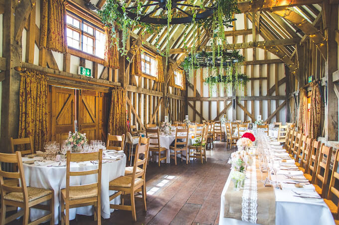 Inside Gate Street Barn, Bramley, with several round tables and a head table setup and decorated.