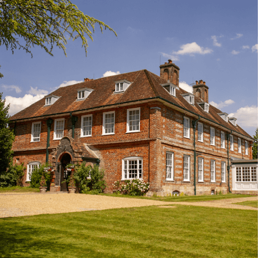 The manor house at Norton Park Hotel in Sutton Scotney. The front and side of the manor house are visible with part of the conservatory in view.