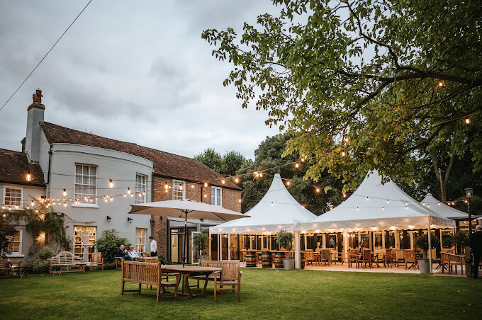 The Old Rectory in Padworth, Berkshire. The garden is shown with lots of festoon lighting and marquees setup alongside the main house.