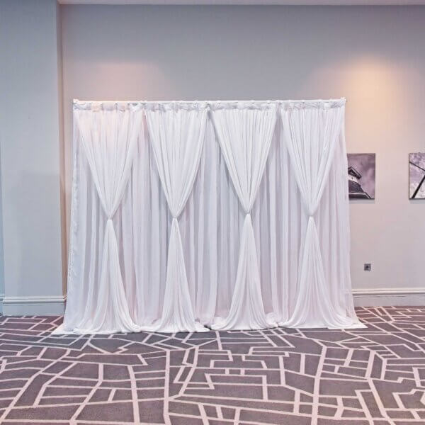 Double layered white drape backdrop with hour glass shape drapes on the front row