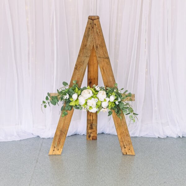 Rustic wood easel with white flowers and eucalyptus on the front