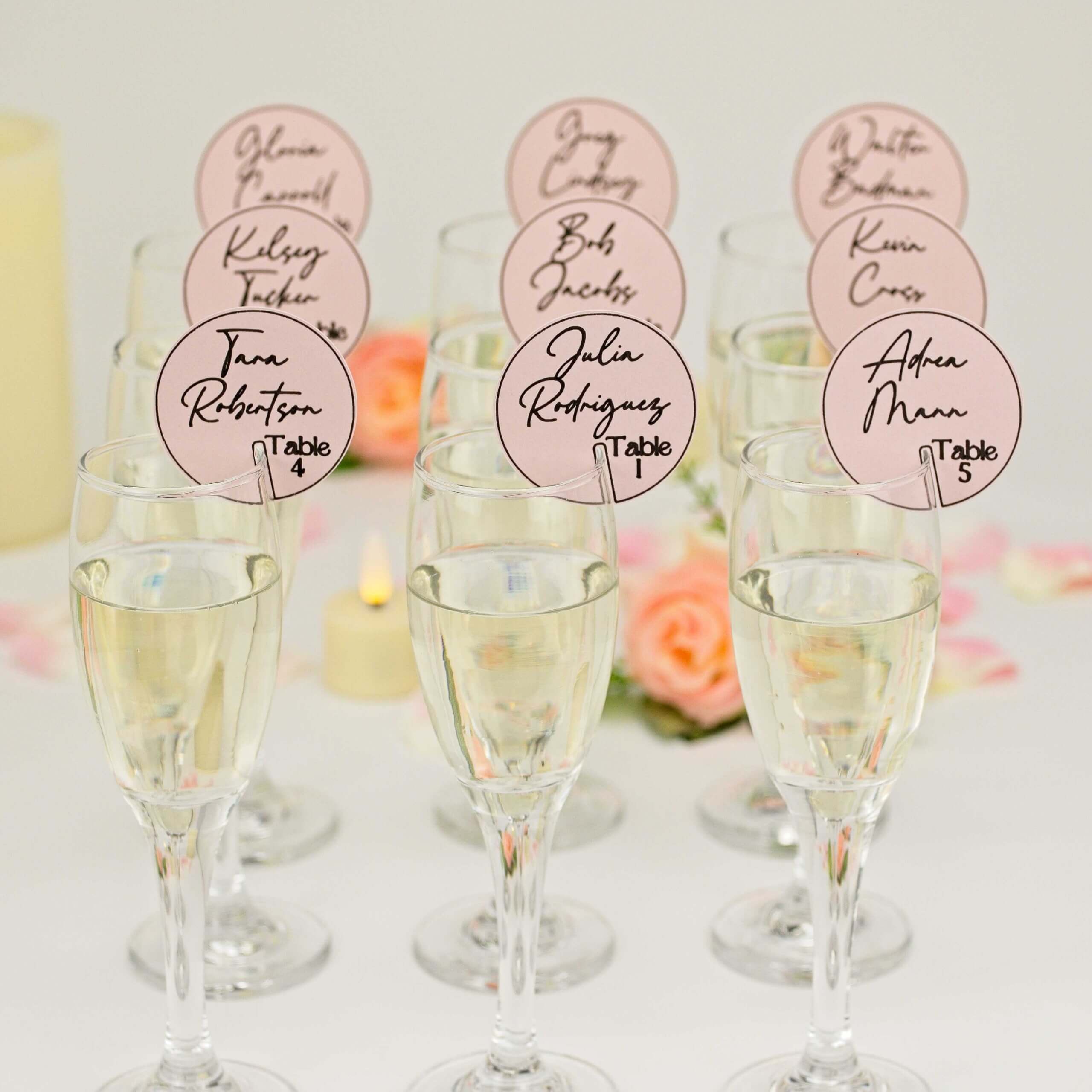 Multiple champagne glasses arranged with pink place tags and petals