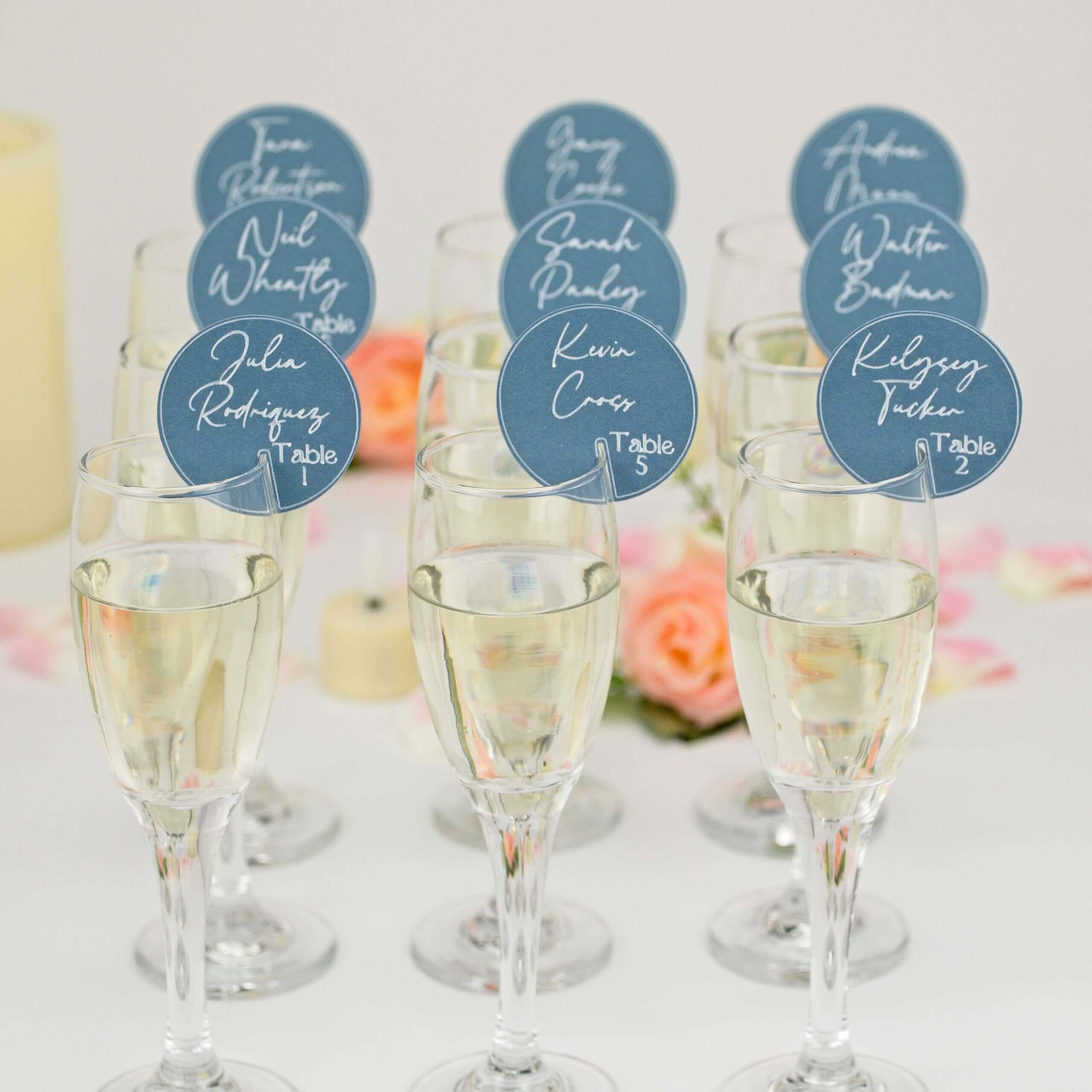 Front view of champagne glasses topped with blue circular place tags