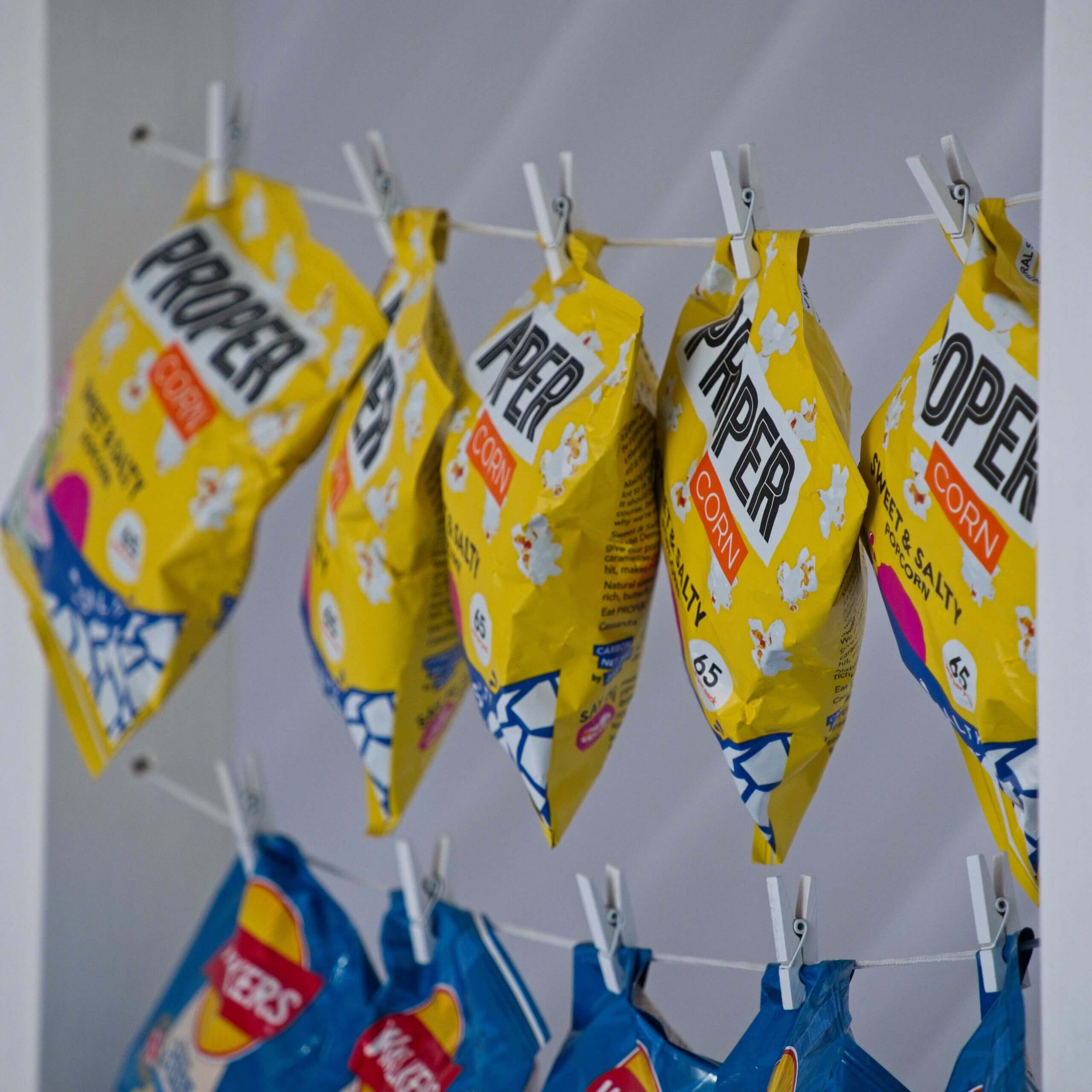 A close up of some crisps being held on white string by small white pegs.